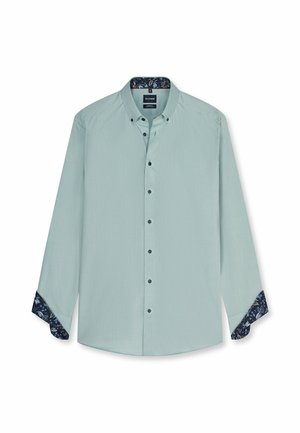Camicia verde chiaro a maniche lunghe con bottoni, con colletto interno e fodera ai polsini a fantasia floreale scura, mostrata distesa con polsini parzialmente piegati all'indietro.