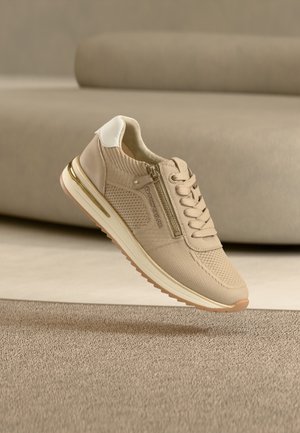 Sneaker beige con tomaia testurizzata e traspirante, puntale posteriore bianco, dettagli dorati e cerniera laterale. Design leggero con suola in gomma.