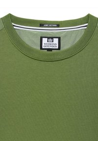 Green cotton t-shirt with a round neck, featuring a contrasting black label with "WEEKEND OFFENDER" and white accent stripes inside the collar.
