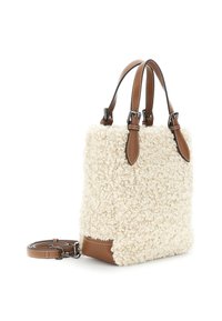 Crème-kleurige pluche tas met krullende textuur, bruine lederen accenten, twee korte handvatten en een afneembare schouderriem.