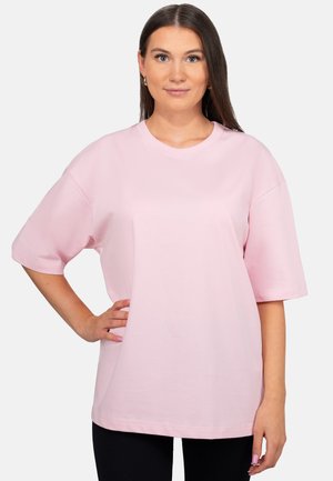 T-shirt rosa chiaro a maniche corte con vestibilità rilassata, scollatura rotonda e tessuto liscio, leggermente strutturato. Senza motivi o accenti visibili.