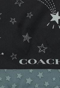 Black fabric featuring scattered silver stars, with textured teal star accents at the bottom, accompanied by a white "COACH" logo.