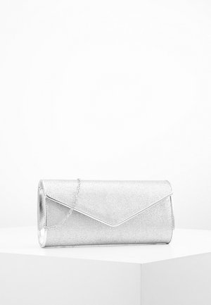Silberne Glitzertasche mit Umschlagklappe und zartem Kettenriemen, präsentiert auf weißem Podest vor schlichter Hintergrund.