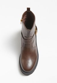 Stivale alla caviglia in pelle marrone con finitura liscia, cinturino con accessorio dorato e punta tonda. Presenta una suola in gomma testurizzata e una fodera interna.