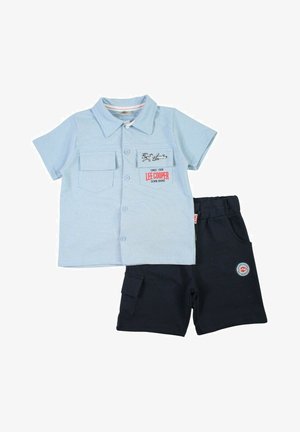 Chemise à manches courtes bleu clair avec poches poitrine et logo, associée à un short noir avec une poche latérale et un patch logo.