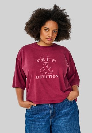 Burgundy oversized T-shirt with a round neckline, featuring white text that reads "TRUE LOVE & AFFECTION," shown with denim shorts.