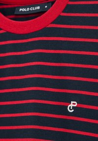 Randig T-shirt med röda och marinblå horisontella ränder, rund halsringning och en liten logotyp i vitt på framsidan. Materialet verkar mjukt.