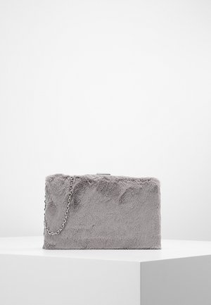 Pochette rectangulaire grise avec une texture douce en fourrure et une bandoulière chaîne argentée, placée sur une surface blanche sur un fond uni.
