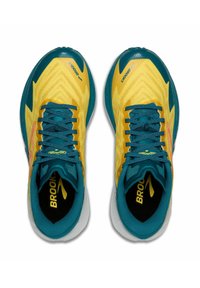 Gele hardloopschoenen met tealaccenten. Voorzien van een gestructureerde bovenkant, platte veters en een gewatteerde zool. Merken zichtbaar op de tong en zijkanten.
