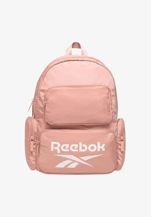 Różowy plecak Reebok z wieloma zamykanymi na zamek kieszeniami i dużym, białym logo Reebok na przedniej kieszeni.