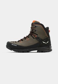 Buty trekkingowe w ciemnozielonej skórze z czarną gumową podeszwą. Posiadają pomarańczowe akcenty, metalowe oczka i średnią wysokość, aby zapewnić wsparcie.