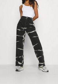Vaqueros de pierna ancha en blanco y negro con efecto tie-dye, de cintura alta, confeccionados en tela de denim, con cierre de botón y acentos de metal plateado.