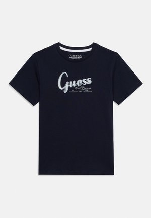 T-shirt noir à manches courtes avec texte blanc "Guess" et design vintage imprimé sur la poitrine, col rond.