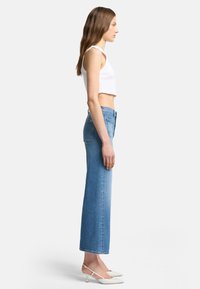 Høyt livd, lyseblå denim jeans med rett passform, med baklommer og en falmet finish, matchende med en tettsittende hvit crop topp.