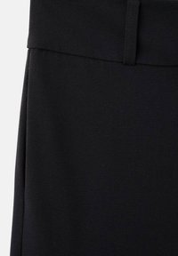 Tessuto nero con una texture liscia, caratterizzato da una vita piatta e linee pulite, che mette in mostra un design semplice e su misura.