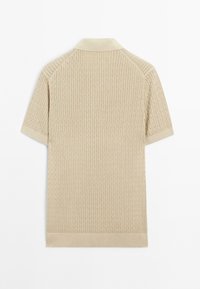 Beige kortærmet polo t-shirt med et struktureret kabelstrikmønster, ribbestrikket krave og manchetter samt en lige kant.