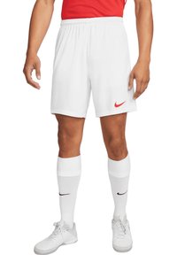 Shorts de sport blancs avec une taille élastique et un logo Nike rouge. Associés à des chaussettes blanches montantes jusqu'aux genoux et à des chaussures de sport blanches.