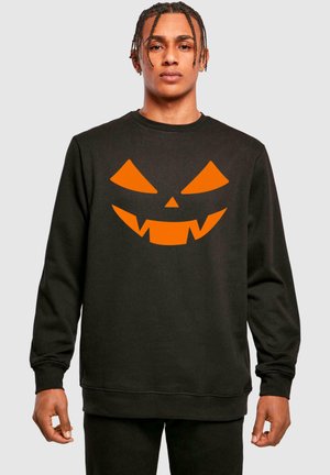 Black sweatshirt featuring a large orange pumpkin face design with jagged teeth; ribbed cuffs and hem.