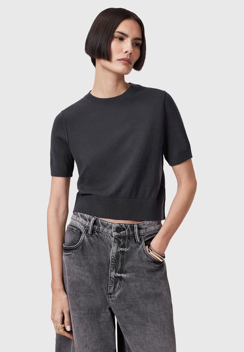 Kortærmet, cropped sort striktrøje parret med højtaljede, falmede grå denimjeans. Minimalistisk design, blød tekstur, afslappet pasform.