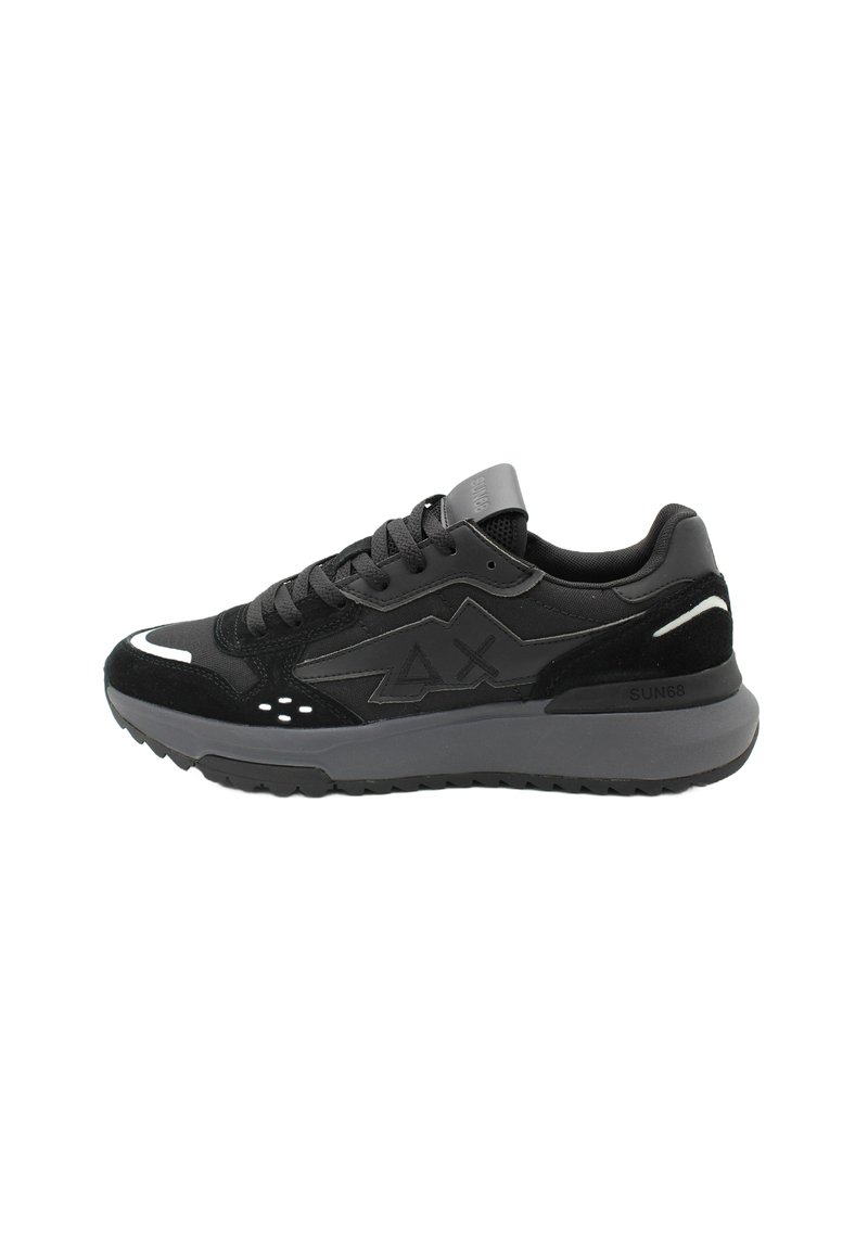 Scarpe da ginnastica nere realizzate con una combinazione di materiali sintetici lisci e suede, dotate di una suola grigia chunky, dettagli in rete e particolari riflettenti.