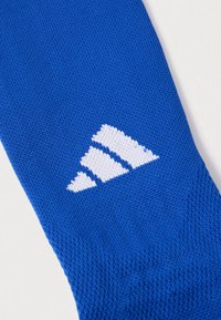 Μπλε πλεκτό ύφασμα με τρεις λευκές διαγώνιες ρίγες που σχηματίζουν ένα τριγωνικό σχέδιο σε επίπεδη επιφάνεια.