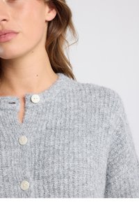 Light gray knitted cardigan with ribbed texture, featuring a small placket and three round buttons at the neckline.