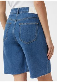 Szorty dżinsowe w średnim niebieskim kolorze, z wysokim stanem, czterema kieszeniami i postrzępionym dołem. Logo na białej skórzanej metce z tyłu.