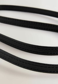 Correas de cuero negro con una textura suave, forma plana y bordes cosidos, dispuestas de forma superpuesta.