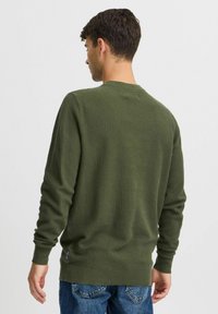 Groene gebreide trui met een textuurafwerking, lange mouwen en een ronde halslijn. Heeft geribde boorden en onderrand. Casual fit.