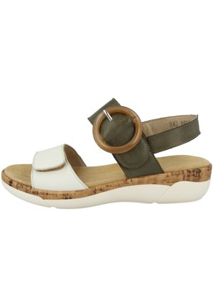 Sandale Velcro avec dessus en cuir blanc, sangle vert olive, semelle intermédiaire en liège en bois et accent rond en bois. Semelle extérieure en mousse légère.