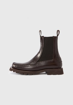 Brown leather Chelsea boots with elastic side panels, rubber sole, and stitched detailing along the toe. Features pull tabs for easy wear.