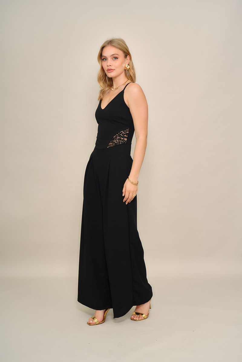 Svart jumpsuit med blonder i sidene, tettsittende overdel og vide ben. Fullført med gullfargede sko med stropper og smykkeaksenter.