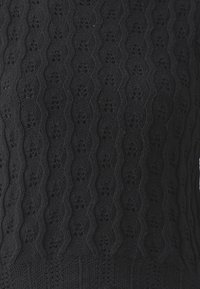 Pull en tricot noir avec un motif ondulé et des découpes florales, surface texturée et ourlet côtelé ajusté.