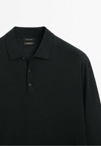 Schwarzes Merinowoll-Polohemd mit gerippter Textur, Drei-Knopf-Leiste und klassischem Kragendesign.