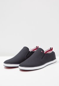 Marina canvas skorna slip-on med vita gummisulor, med ett röd- och vitfärgat foder och en liten logotyp på sidan.