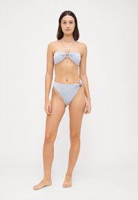 Világoskék bikini szett, csavart toppal, kör alakú díszítéssel és magas derekú alsó résszel, hasonló részletezéssel, sima anyagból készült.