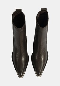 Bottines en cuir marron avec un bout pointu, une surface texturée, un design de broderie subtile et un accent argenté sur le bord avant.