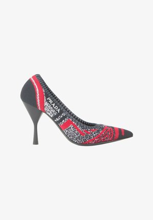 Zapato de tacón alto puntiagudo negro y rojo con textura de punto y marca blanca en el lateral.