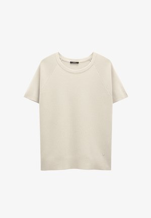 Jasno beżowy sweter z krótkim rękawem, okrągłym dekoltem i ściągaczami, wykonany z miękkiej dzianiny. Mały detal z logo na dole.