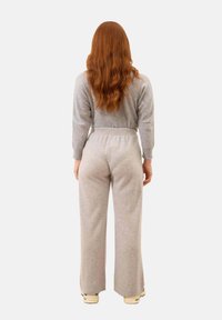 Šedý set volnočasového oblečení zahrnující dlouhý rukáv a široké kalhoty, vyrobený z měkké látky s elastickým pasem. Zobrazeno ze zadní strany.