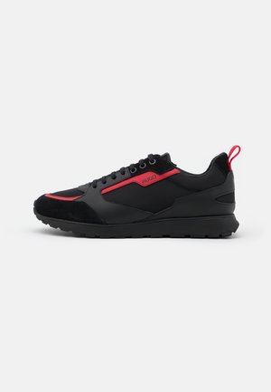Sneaker nero basso con dettagli rossi, chiusura con lacci frontale e logo "HUGO" sul lato, con linguetta sul tallone.