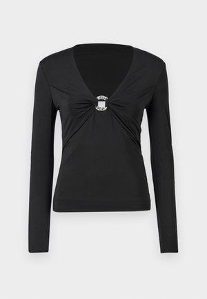 Maglietta nera a maniche lunghe con scollo a V, caratterizzata da un centro annodato con un dettaglio decorativo in anello d'argento. Tessuto morbido e aderente, design minimalista.