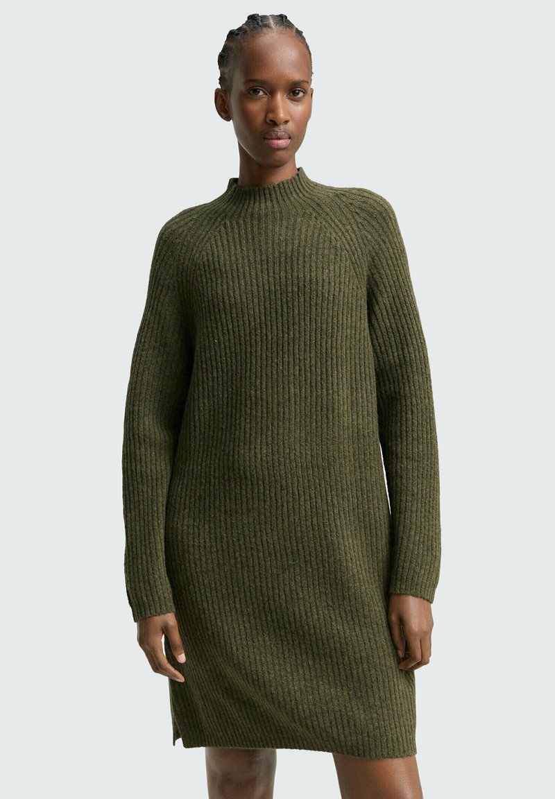 Rippiges, übergroßes olivgrünes Strickkleid mit hohem Kragen und langen Ärmeln, mit geradem Schnitt und kleinen Seitenschlitzen.