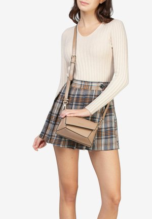 Tan skuldertaske med geometrisk design; glat tekstur og justerbar rem; parret med et rutet skørt og ribbet top.