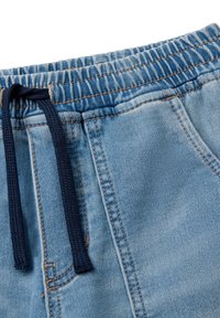 Pantalones cortos de mezclilla azul claro con cinturilla elástica y cordón de tiro azul oscuro, que muestran costuras detalladas y un bolsillo frontal.