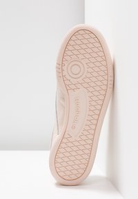 Jasnobrązowy sneaker z teksturowaną gumową podeszwą z wzorzystym bieżnikiem i wytłoczonym logo. Cholewka jest gładka i minimalistyczna.