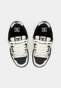 DC sneakers featuring a black and cream colorway, textured leather upper, padded collar, and white laces, designed for durability and comfort.