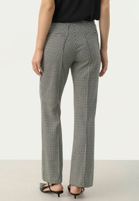 Zwart-wit houndstooth-gepatenteerde broeken met een rechte pijp. Gemaakt van textuurstof, met een hoge taille en geen zichtbare zakken.