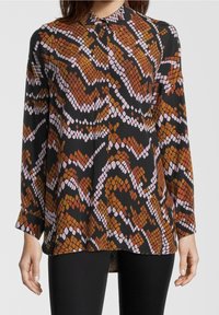 Langarmhemd aus leichtem Stoff mit einem auffälligen Schlange-Design in Schwarz, Orange und Pink, versehen mit einem spitzen Kragen und Knopfleiste.