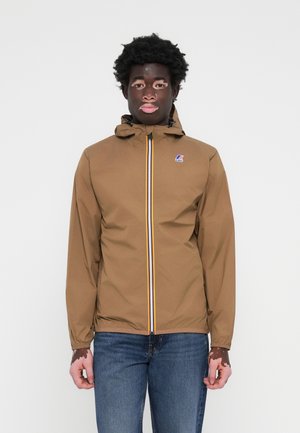 Brun vanntett jakke med hette, med glidelås foran og en flerfarget stripe samt en liten logo på brystet.